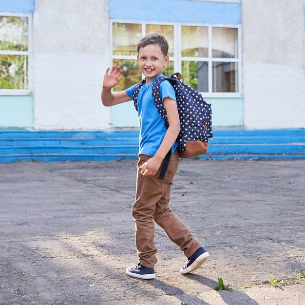 Garçon rentre de l'école avec son cartable