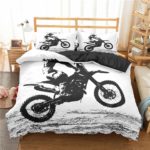 Parure de lit dans une chambre d'enfant , la parure est blanche avec une motocross en train de cabrer en noir et blanc