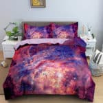 Dans une chambre un lit, avec table de chevet de chaque coté, est couvert d'une parure complete de lit avec des étoiles et des galaxies dans les tons orangés