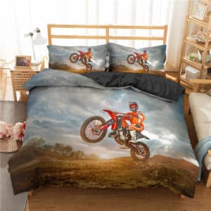 Dans une chambre d'enfant , est installée sur le lit une parure complète dans les tons gris sur laquelle on voit une motocross en train de faire un saut