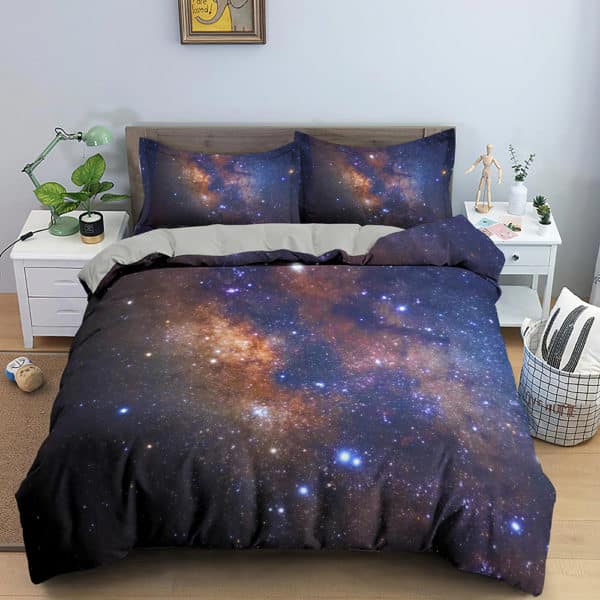 Dans une chambre un lit, avec table de chevet de chaque coté, est couvert d'une parure complete de lit avec des étoiles et des galaxies