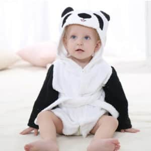 Petit bébé assis sur un sol blanc et portant un peignoir de bain blanc et noir dont la capuche représente une tête de panda