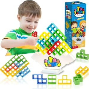 Petit garçon souriant jouant avec le jeu d'équilibre Tetris Tower sur une table, avec la boîte du jeu à côté, sur fond blanc