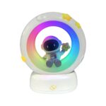 Veilleuse garçon astronaute rechargeable disposant d'une lumière LED RGB en forme de lune où se tient assis un petit astronaute mignon en combinaison.