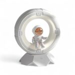 Veilleuse astronaute LED tactile pour garçon représentant un astronaute assis sur un cercle semblable une lune sur fond blanc