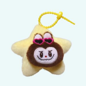 Peluche style Labubu porte-clé en forme d'étoile jaune avec une attache jaune au-dessus. Au centre de l'étoile, le visage de Labubu marron avec des lunettes de soleil roses en forme de cœur. Sur fond bleu ciel.