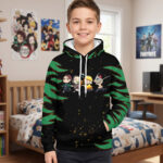 Un petit garçon souriant porte un Sweat Demon Slayer kawaii avec personnages chibi, affichant des motifs verts et noirs sur les manches, dans une chambre d'enfant.