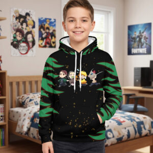 Un petit garçon souriant porte un Sweat Demon Slayer kawaii avec personnages chibi, affichant des motifs verts et noirs sur les manches, dans une chambre d'enfant.