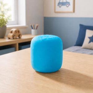 Un jouet anti-stress sensoriel Needoh Mello Mallo bleu en forme de petit coussin, posé sur une table dans une chambre d’enfant.
