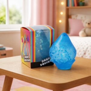 Un jouet sensoriel anti-stress Needoh en forme de goutte d'eau bleu, posé sur une table avec sa boîte colorée dans une chambre d'enfant.