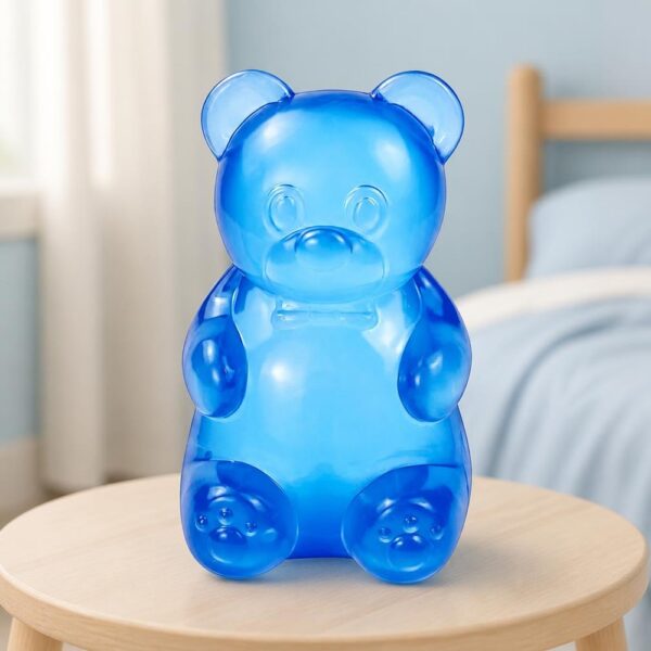 Un jouet Squishy Needoh garçon anti-stress en ourson translucide bleu posé sur une petite table, dans une chambre lumineuse.