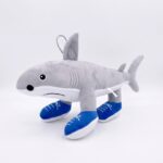Une peluche grise en forme de requin portant des chaussures de basket bleues, avec une boucle de porte-clé, sur un fond blanc. Peluche porte-clef Italian Brainrot Requin Basket