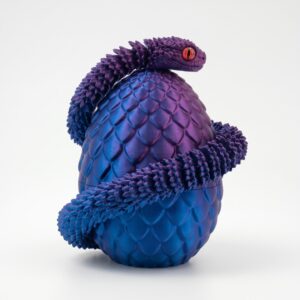 Une figurine oeuf de serpent articulé violette et bleue, avec un serpent texturé enroulé autour, posée sur un fond blanc.